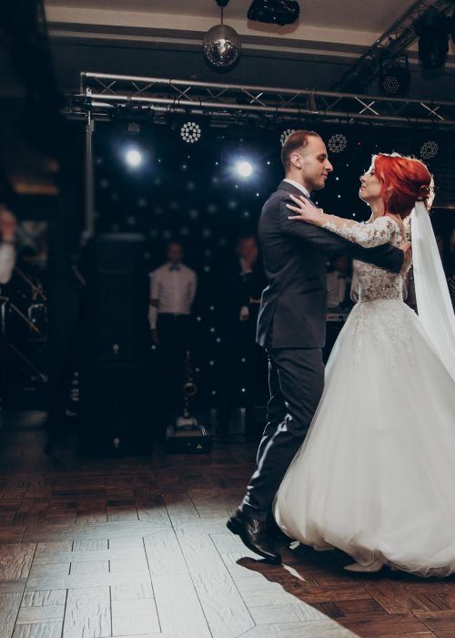 happy bride and stylish groom dancing at wedding reception.